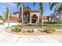 Inviting two-story home featuring a red roof, palm trees, arched entryway, and a well-manicured lawn at 4404 Lake In The Woods Dr, Spring Hill, FL 34607