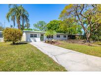 Charming single-story home with a lush green lawn, landscaped garden beds, and a long concrete driveway at 4517 S Hale Ave, Tampa, FL 33611