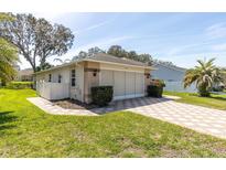 Charming single-story home with brick accents, a paved driveway, and well-maintained landscaping under a clear blue sky at 7472 Clearmeadow Dr, Spring Hill, FL 34606
