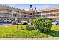 Charming condo building with castle-like architectural details, manicured lawn, and ample parking spaces at 2457 Ecuadorian Way # 73, Clearwater, FL 33763