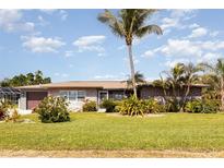 Charming single-story home with manicured lawn and mature palm trees at 4 Oakland Hills Ct, Rotonda West, FL 33947