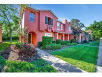 Charming two-story townhome featuring verdant landscaping and vibrant red stucco facade at 6843 Se Dartmouth Hill St, Riverview, FL 33578