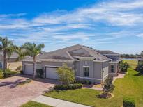 Stunning single-story home boasts a three-car garage, manicured lawn, and brick-paved driveway on a sunny day at 720 Chipper Dr, Sun City Center, FL 33573