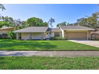 Single Gathering home boasting a manicured lawn, neutral paint, rock columns, and attached two car garage at 864 Pinewood W Ter, Palm Harbor, FL 34683