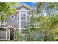 Charming two-story home with gray siding, white trim, and a well-manicured front yard, framed by lush trees and flowering plants at 506 S Willow Ave # 7, Tampa, FL 33606