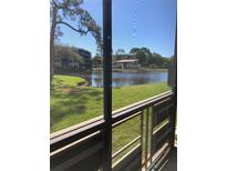 Screened balcony showing a pond view with green grass and community buildings at 6070 80Th N St # 109, St Petersburg, FL 33709