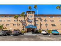 Spacious multi-level condo building with palm trees, covered entrance and ample parking spaces for residents and visitors at 6100 Gulfport S Blvd # 414, Gulfport, FL 33707
