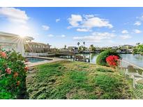 Waterfront backyard featuring a pool, dock, and lush landscaping with tropical plants at 720 Capri Blvd, Treasure Island, FL 33706