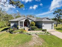 Charming single-story home with a lush front lawn, flower beds, and a two-car garage at 8437 Indies Dr, Hudson, FL 34667