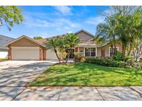 Beautiful home featuring well-manicured front yard with lush landscaping, palm trees, and a three car garage at 8746 Tantallon Cir, Tampa, FL 33647