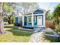Charming blue bungalow with a cozy front porch and vibrant turquoise chairs at 8909 N Dexter Ave, Tampa, FL 33604