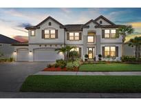 Elegant two-story home featuring a three-car garage, beautiful landscaping, and a tile roof at 33105 Kateland Dr, Wesley Chapel, FL 33545