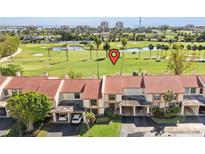 Golf course community featuring a lovely lake, palm trees, and multiple carports for each townhome at 6140 Sun Blvd # 5, St Petersburg, FL 33715