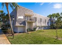 Charming condo exterior with a balcony, lush lawn, and mature trees on a sunny day at 720 Lyndhurst St # 1121, Dunedin, FL 34698
