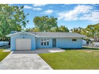 Charming single-story home featuring a well-manicured lawn and a spacious driveway leading to an attached garage at 7323 Andre Dr, Zephyrhills, FL 33541
