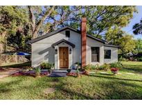 Charming cottage-style home with brick chimney, updated paint, tidy landscaping and mature trees in the front yard at 1006 E River Cove St, Tampa, FL 33604