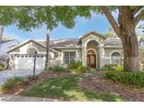 Charming single-story home with mature trees, arched entry, and well-maintained landscaping at 13703 Whitebark Pl, Tampa, FL 33625