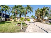 Charming single-story home featuring a well-manicured lawn, brick driveway, and tropical palm trees at 4126 Harrisburg Ne St, St Petersburg, FL 33703