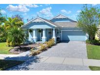 Charming, light blue single-Gathering home featuring a brick driveway, manicured landscaping, and a welcoming front porch at 5128 Admiral Pointe Dr, Apollo Beach, FL 33572