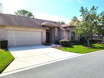 Charming home with brick accents, a well-manicured lawn, and a wide driveway leading to the garage at 7392 Meadow Brook Ln, Spring Hill, FL 34606