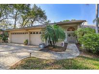 Charming home featuring a brick walkway, a three-car garage, and beautiful landscaping with mature trees at 8823 Crescent Forest Blvd, New Port Richey, FL 34654