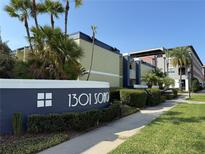 The condo is a multi-story property with a well-kept lawn, mature trees, and a sign that says 