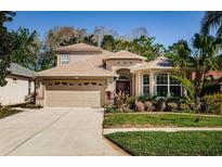 Beautiful two-story home with a landscaped front yard, mature trees, and an attached garage at 15925 Pond Rush Ct, Land O Lakes, FL 34638