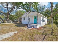 Charming cottage-style home featuring a bright blue front door and freshly painted white exterior at 2111 E Ellicott St, Tampa, FL 33610