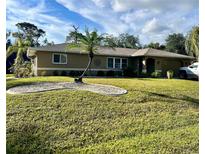 Charming single-story home featuring a lush green lawn and a decorative palm tree in the front yard at 229 Tazewell Dr, Port Charlotte, FL 33954