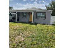 Charming single-story home with a yellow front door, carport, and cozy front yard at 3106 W Dewey, Tampa, FL 33607