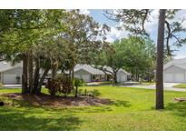 Well-maintained front yard of a charming single-story home, surrounded by mature trees and lush greenery at 39650 Us Highway 19 N # 615, Tarpon Springs, FL 34689