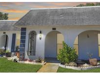 Charming condo features a light exterior, arched entryways, and manicured landscaping at 4229 Redcliff Pl, New Port Richey, FL 34652