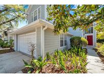 Charming home exterior featuring a two-car garage, red front door, and lush landscaping at 5159 Sterling Manor Dr, Tampa, FL 33647