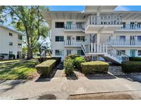 White condo building featuring well-maintained landscaping and inviting staircases at 8454 111Th St # 201, Seminole, FL 33772