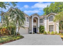 Elegant two-story home with stucco exterior, arched windows, lush landscaping, and a concrete driveway leading to an attached garage at 9314 Heritage Oak Ct, Tampa, FL 33647