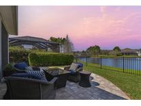 Relaxing patio with waterfront view, outdoor seating, and screened-in lanai beyond at 14885 Caravan Ave, Odessa, FL 33556