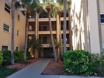 Three story condominium building with balconies surrounded by mature landscaping and palm trees at 2525 W Bay Dr # A11, Belleair Bluffs, FL 33770