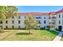Condo with red tile roof and lush green lawn and mature tree in front at 2700 Bayshore Blvd # 4204, Dunedin, FL 34698