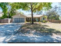 Charming single-story home with a well-maintained lawn, mature tree, and a two-car garage at 275 S Highland Ave, Tarpon Springs, FL 34689