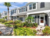 Charming townhome with gray stucco, black shutters, and professionally landscaped front yard at 297 Countryside Key Blvd, Oldsmar, FL 34677