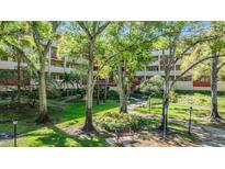 Exterior view of building with lush landscaping, mature trees, and pathways at 3076 Eastland Blvd # 305, Clearwater, FL 33761