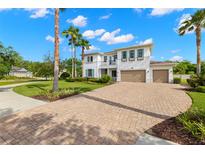 Stunning two-story white home with a three-car garage, brick driveway, and lush landscaping at 3226 Cordoba Ranch Blvd, Lutz, FL 33559