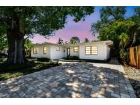 Charming single-story home with a brick driveway, lush landscaping, and a fresh, white exterior paint at 3818 W San Miguel St, Tampa, FL 33629