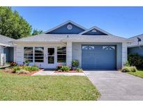 Charming single-story home featuring a well-manicured lawn and a blue garage door at 6644 Juniper Ct, Zephyrhills, FL 33542