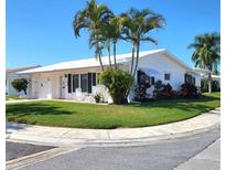 Charming single-story home with a well-manicured lawn, palm trees, and a bright white exterior at 9870 36Th N Way, Pinellas Park, FL 33782