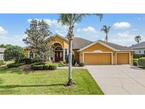 Inviting single-story home with manicured lawn, mature trees, and a charming double-door entrance at 13514 Thoroughbred Dr, Dade City, FL 33525