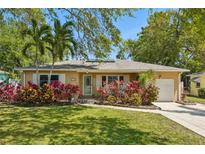 Charming single-story home featuring lush landscaping, palm trees, and a welcoming front porch at 1808 Gray S St, Gulfport, FL 33707