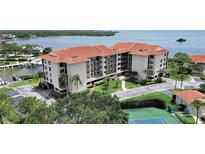 Beautiful waterfront condo building featuring a red tile roof and lush landscaping at 1810 Mariner Dr # 207, Tarpon Springs, FL 34689