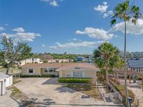 Single-story home with a long driveway, palm trees, and beautiful landscaping at 1863 Venetian Point Dr, Clearwater, FL 33755