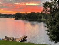 Picturesque lake view with a private dock and a vibrant sunset reflecting on the water at 2327 Shirecrest Cove Way, Lutz, FL 33558